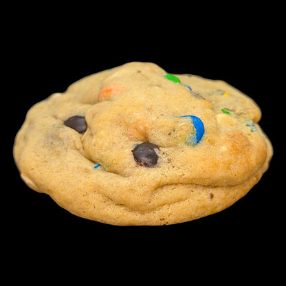 Cookie with chocolate chips and colorful candies on a black background